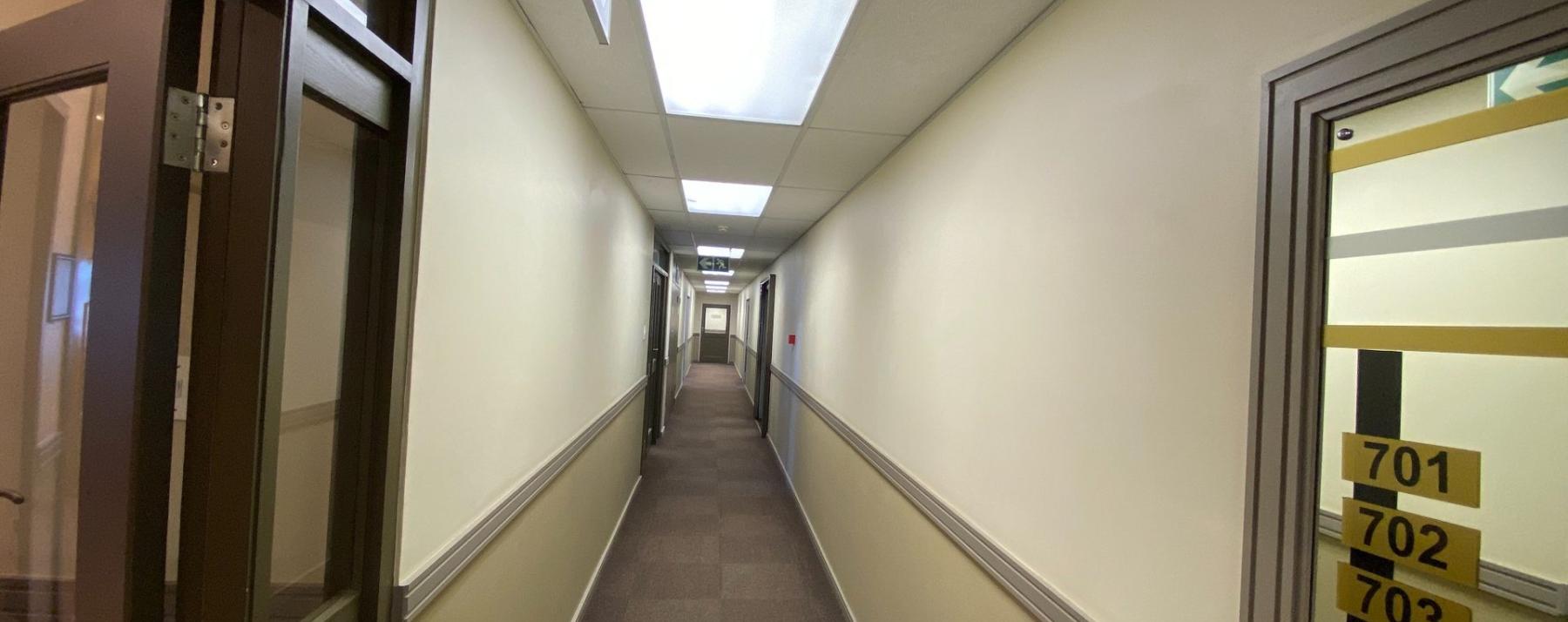 Long office hallway with neutral finishes and office suite signage