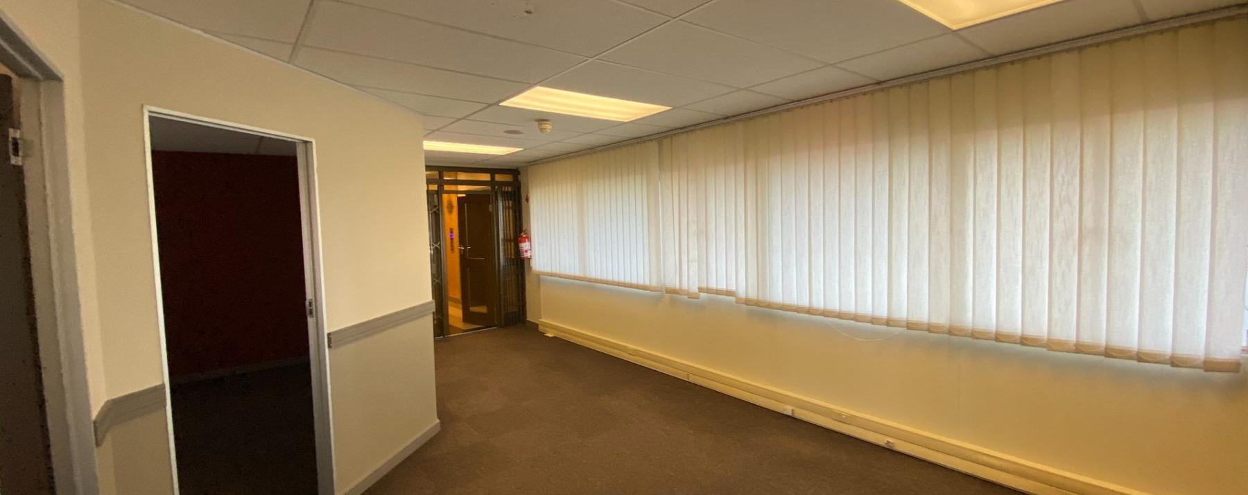 Spacious open-plan office area with natural light and vertical blinds