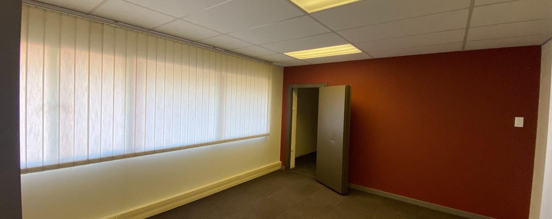 Office suite with red feature wall and large window blinds