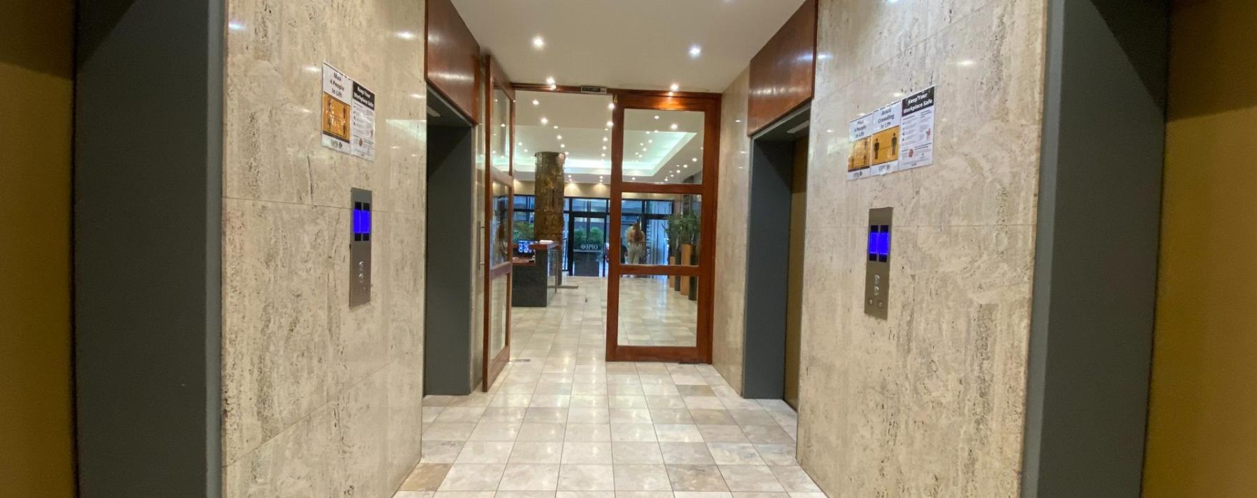 Marble-finished office lift lobby with modern elevators
